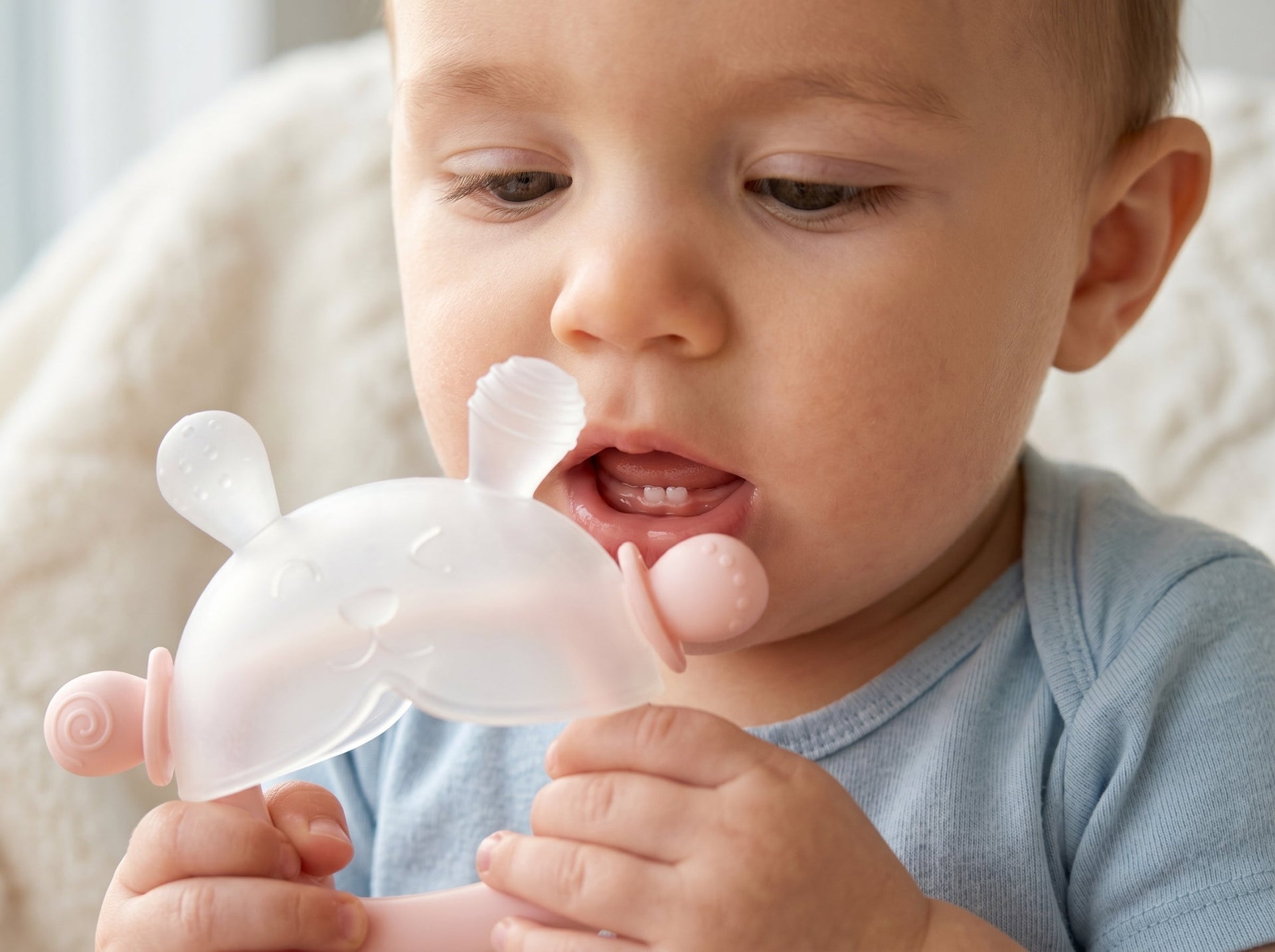 Close-up of a 6-month-old infant showing primary lower central incisor teeth eruption while using a safe silicone soothing tool.